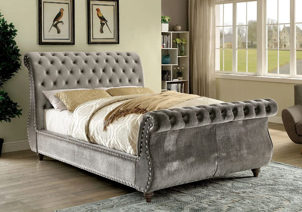 Fancy gray sleigh bed frame with dark hardwood floors and a gray carpet in the front