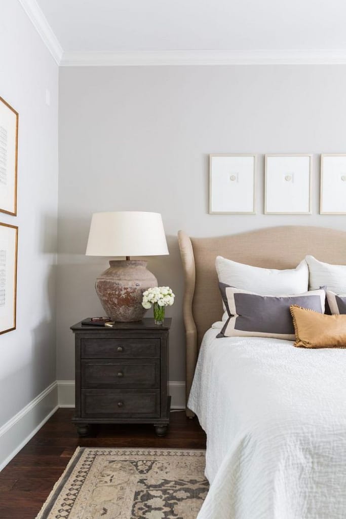 Neutral color bed linens with a table lamp next to the bed 