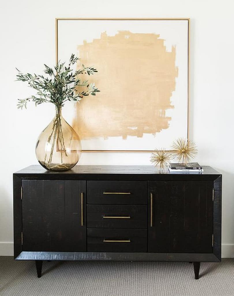 Black credenza with 2 cabinets and 3 drawers and a plant on top for decor