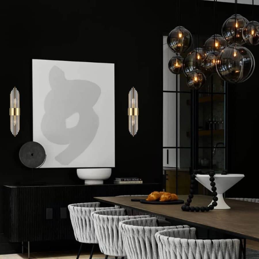 Dining room with black walls and 2 long golden wall sconces for a luxurious look