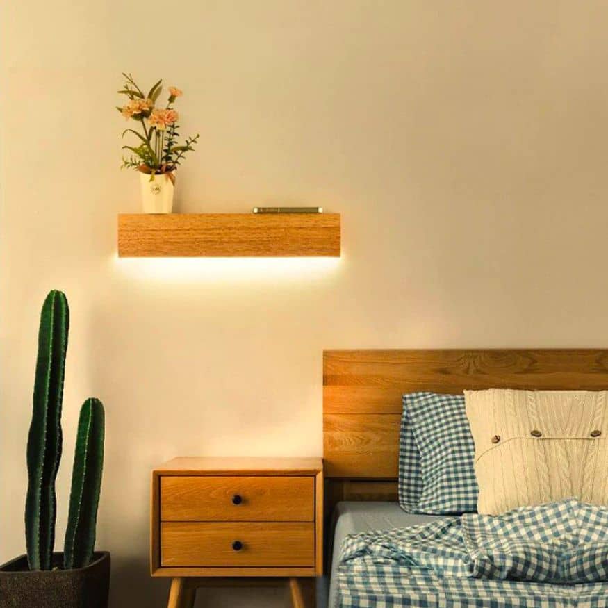 Floating bedside shelf with light casting onto a bedside table beneath it for modern bedside lighting