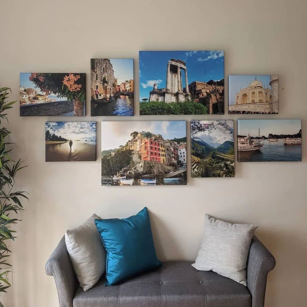 Travel themed gallery wall on a white wall above a small gray couch