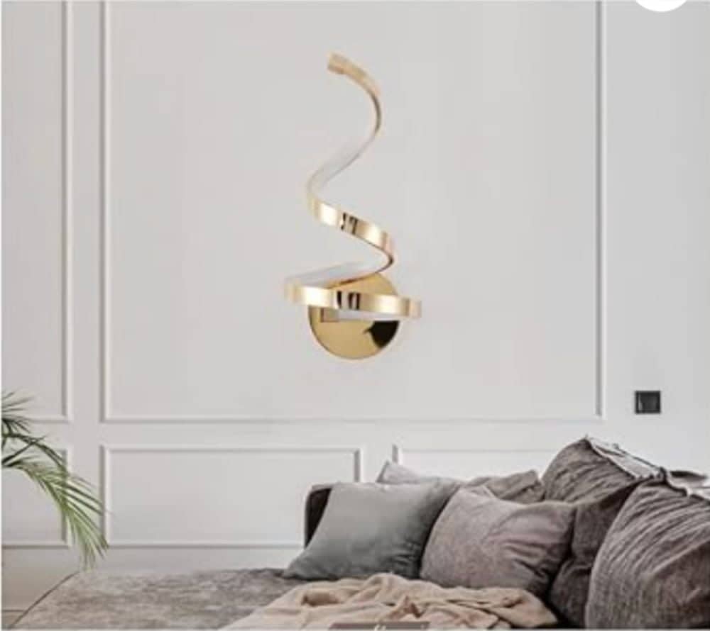 Spiral wall sconce on a white wall with couch in front 