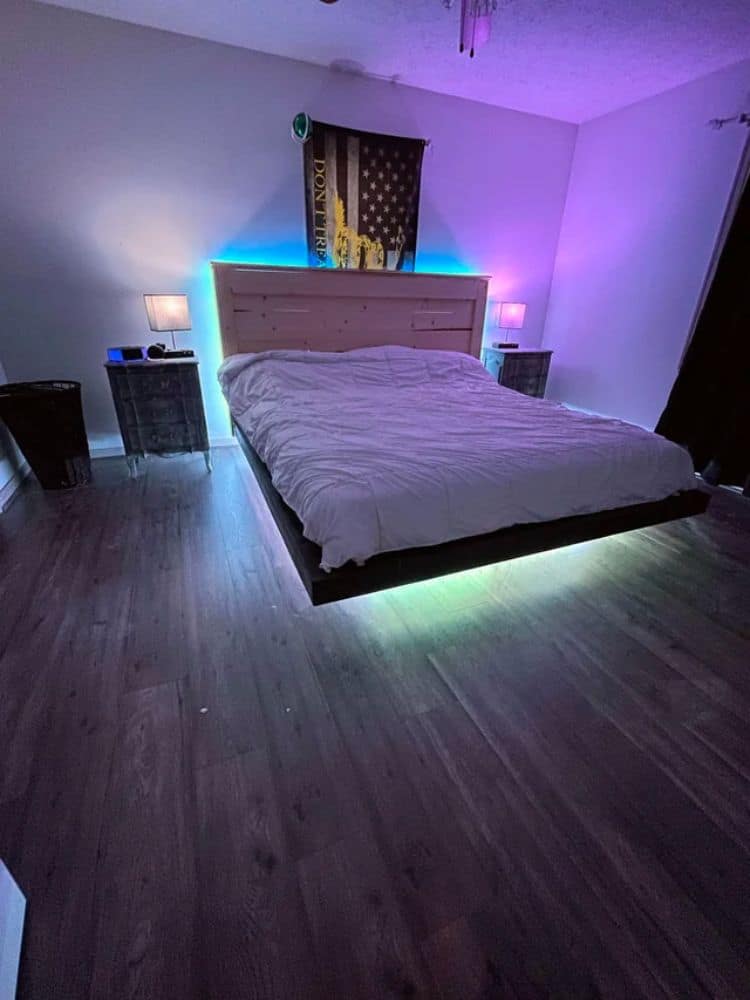 Colorful ambient lighting under bed with a hardwood floor