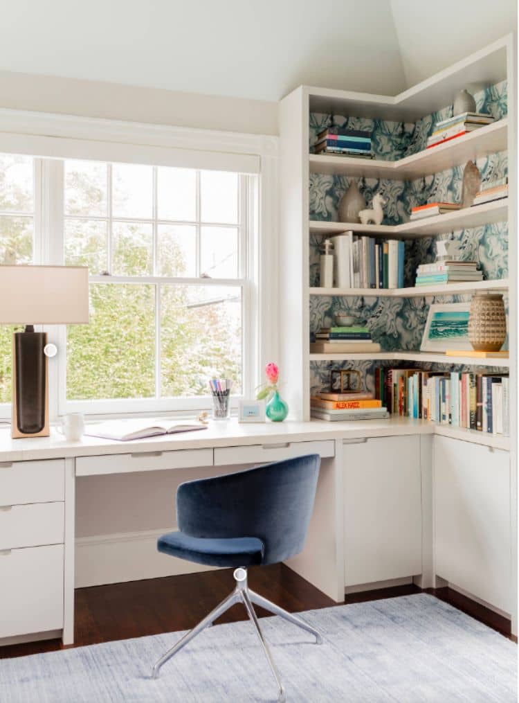 White desk facing window for extra natural light with a bookshelf in the corner