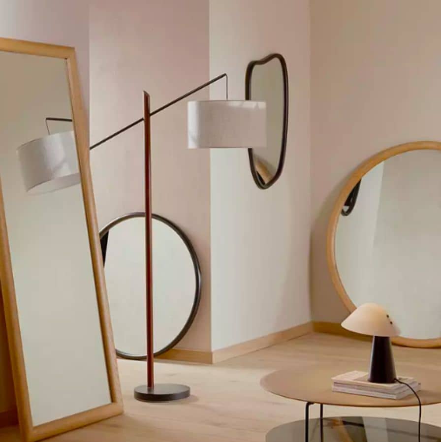 Mirrors scattered around in beige bedroom with a floor lamp in the middle