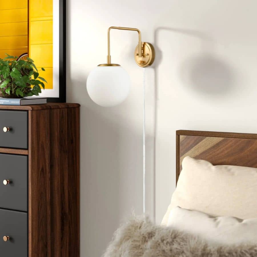 White and gold glass globe wall sconce on bedside wall