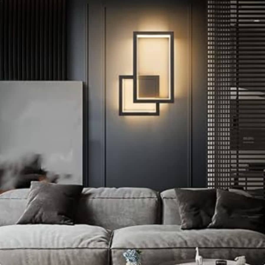 Warm white glow coming from a rectangular modern wall sconce on a gray wall