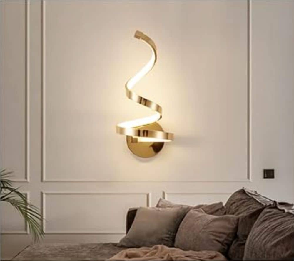 Spiral wall sconce with warm white light coming from it on a wall with a couch in front